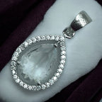 Silver teardrop pendant with faceted clear crystal and pave halo, flat-lay close-up