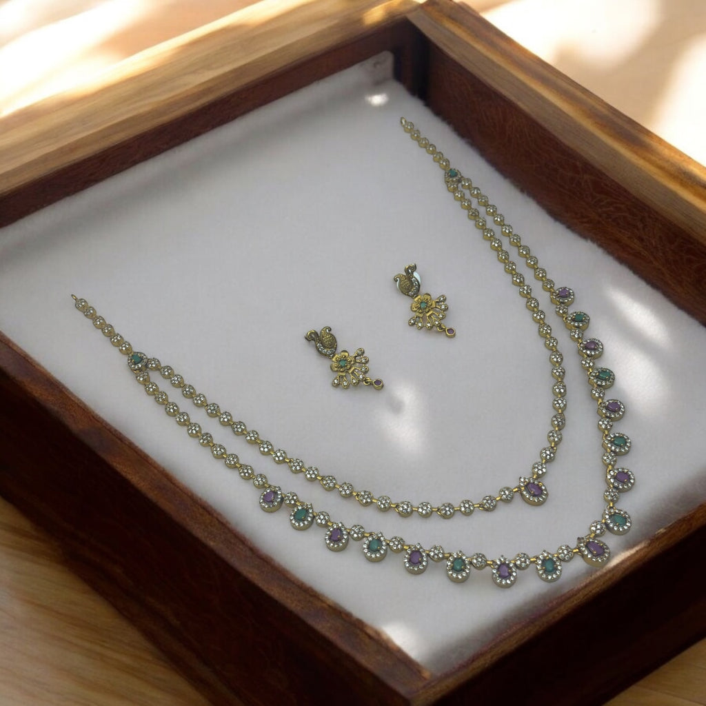 Antique gold necklace set with multi-colour green and purple stones and matching stud earrings, flat-lay in wooden box