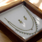 Antique gold necklace set with multi-colour green and purple stones and matching stud earrings, flat-lay in wooden box