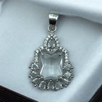 Silver-tone emerald-cut crystal pendant with pear and round CZ teardrop halo, flat-lay close-up