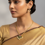 Antique gold floral necklace set with green and pink stones and pearl drops, flat-lay on autumn leaves