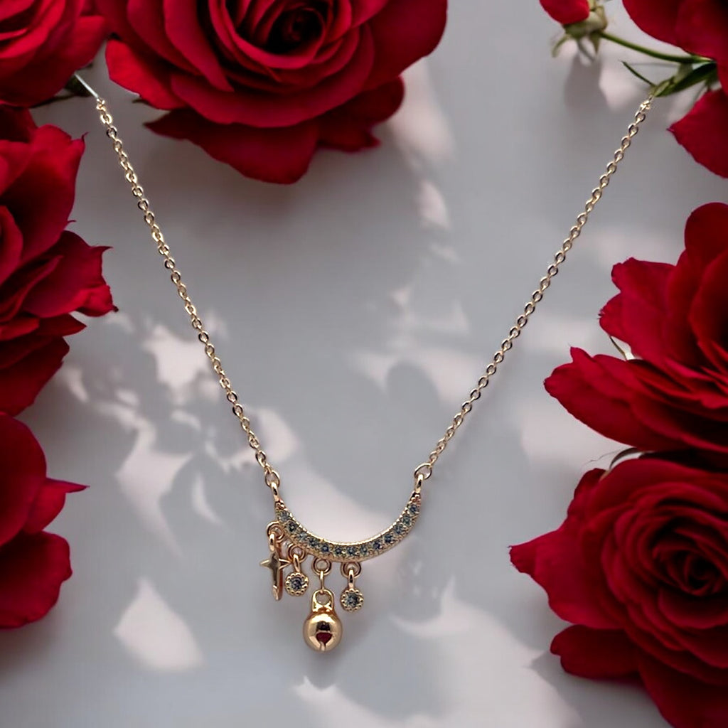 Gold-toned crescent moon pendant necklace with sparkling stones and star, bead and charm dangles, flat-lay with red roses