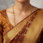 Gold chain necklace with floral-link vine design, flat-lay with purple flowers