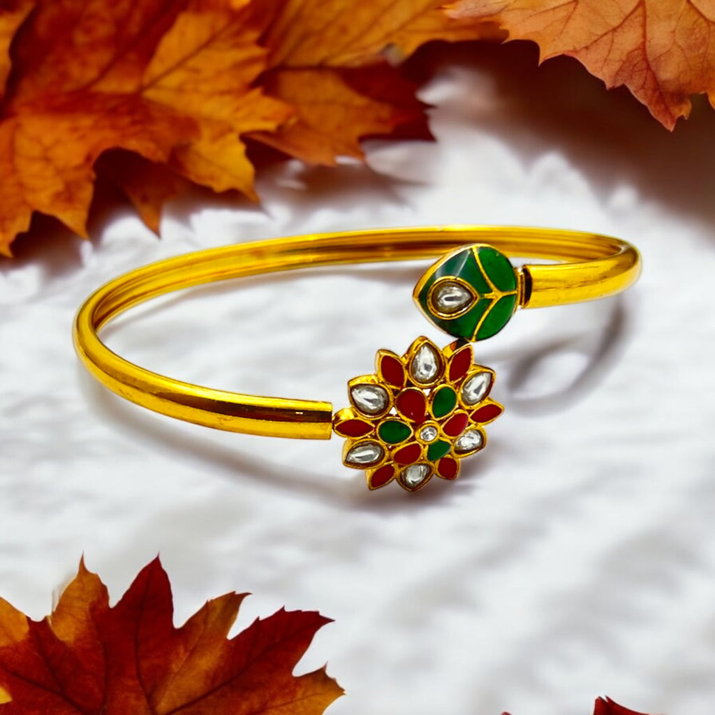 Gold-plated floral Kundan cuff bracelet with green, red and white stones, worn on wrist close-up