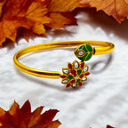 Gold-plated floral Kundan cuff bracelet with green, red and white stones, worn on wrist close-up