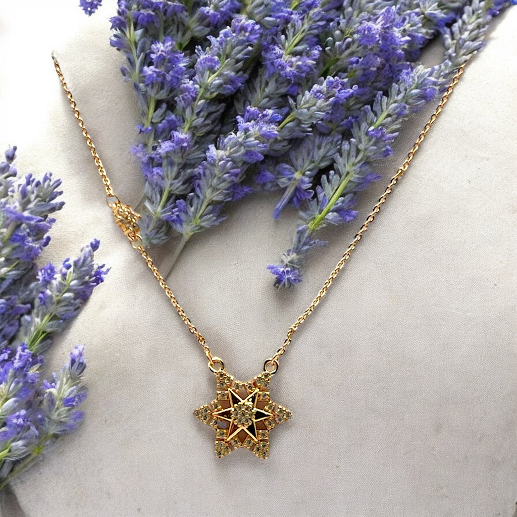 Gold-toned starburst pendant necklace with sparkling stones, worn on model with a saree