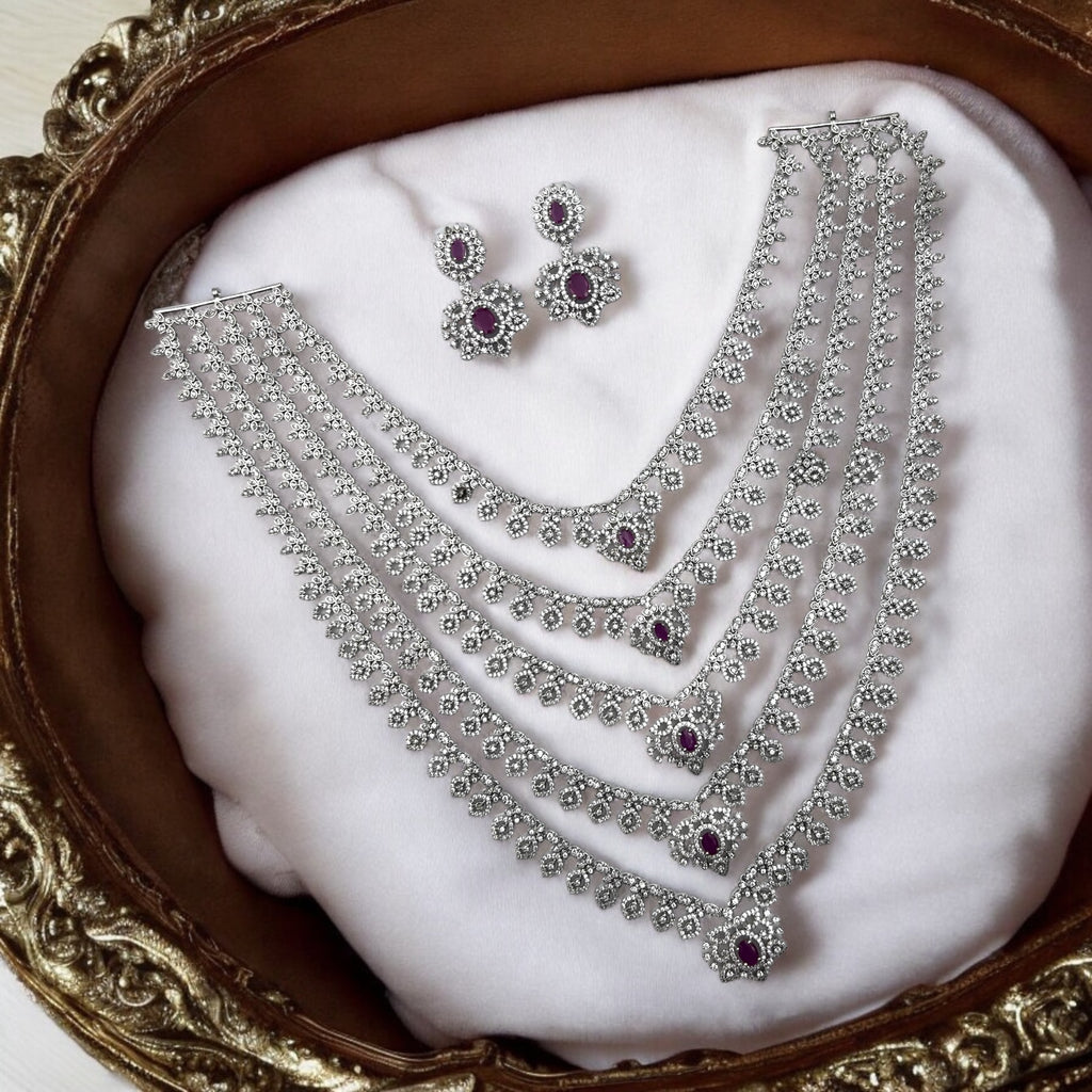 Silver-tone ruby & white stone multi-layered necklace set with drop earrings, worn on model with green saree