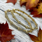 Gold-plated CZ pave bangles with floral accents, worn on wrist poolside showing waterproof shine