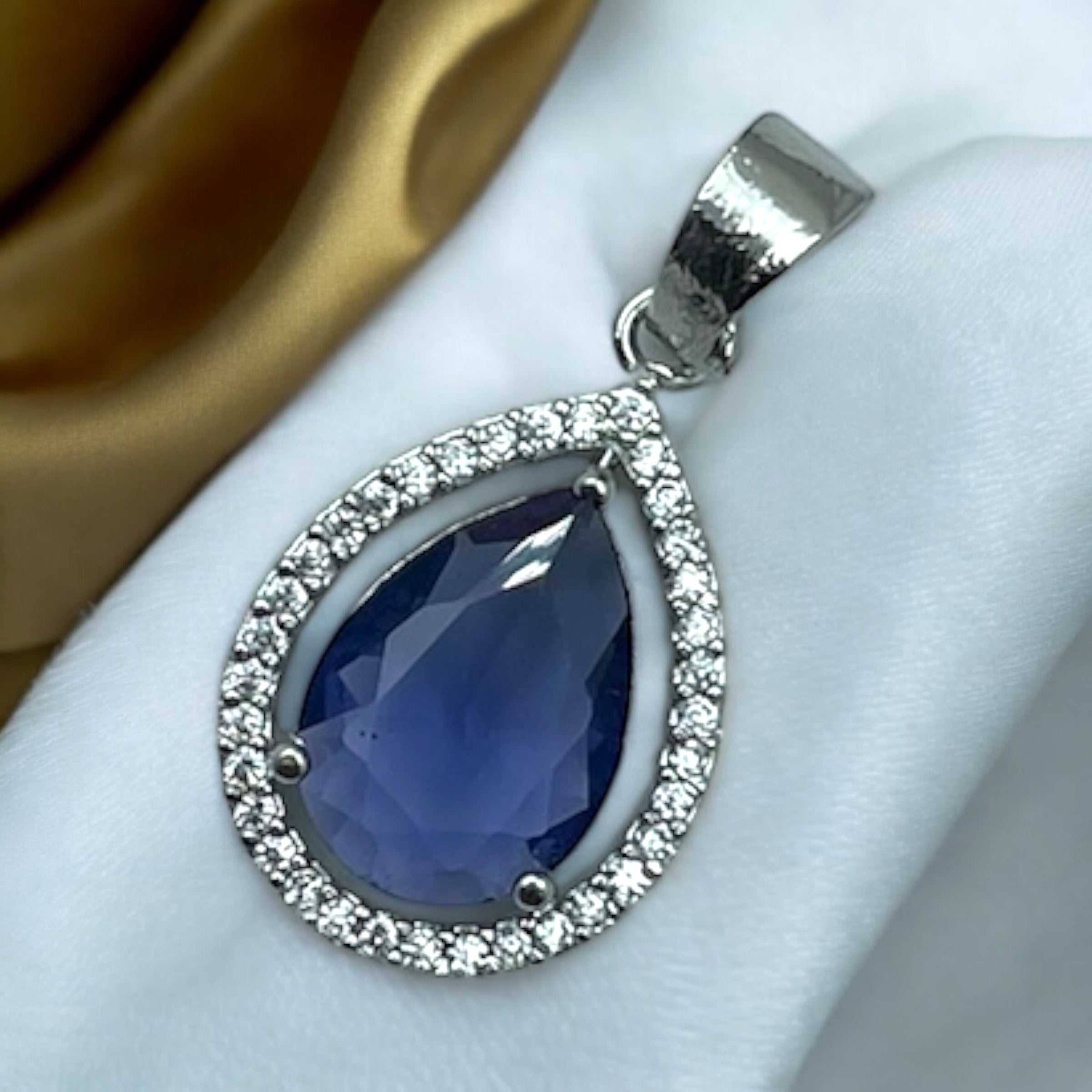 Silver-tone blue drop pendant with pear stone and crystal halo, worn on model with festive saree