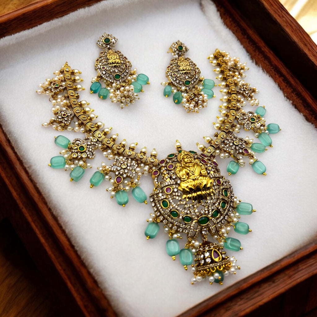 Gold Lakshmi temple necklace set with green, ruby and pearl accents, worn on model with matching earrings