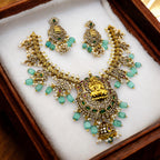 Gold Lakshmi temple necklace set with green, ruby and pearl accents, worn on model with matching earrings