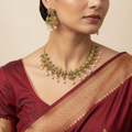 Antique gold-toned necklace set, floral temple design with ruby, emerald and pearl drops, flat-lay with autumn leaves