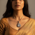 Silver-tone emerald-cut crystal pendant with pear CZ halo, worn on a woman's neck on a fine chain