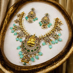 Gold Lakshmi temple necklace and earrings set with CZ stones and pearls, flat-lay in ornate gold frame