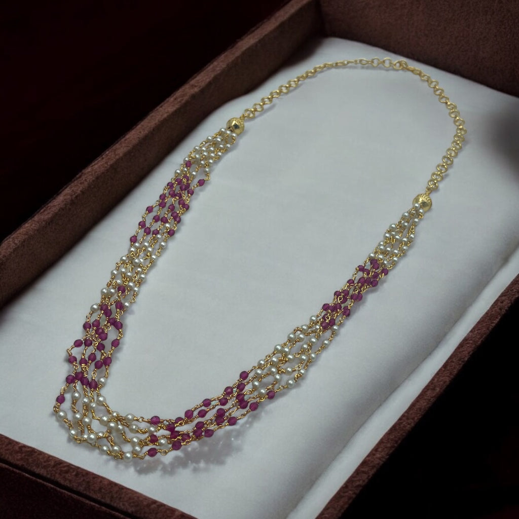 Gold-plated multi-strand necklace set with ruby-toned beads and pearls, worn on model with a gold saree