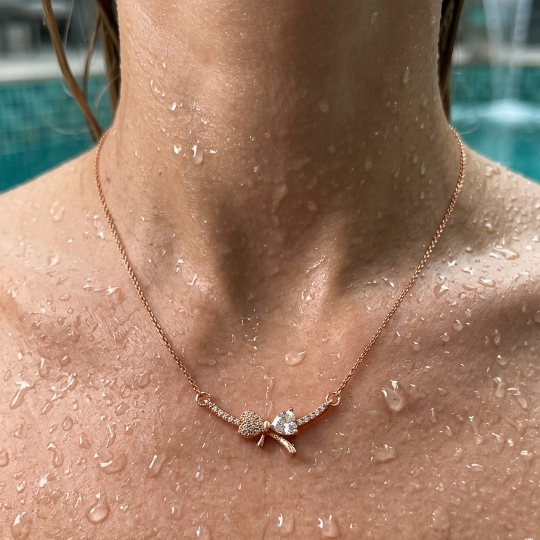 Necklace with a bow pendant on a person with water droplets on skin, pool background