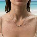 Rose gold Mini Bow pendant necklace with pave crystal bow, worn on neck with sparkling heart accent stone