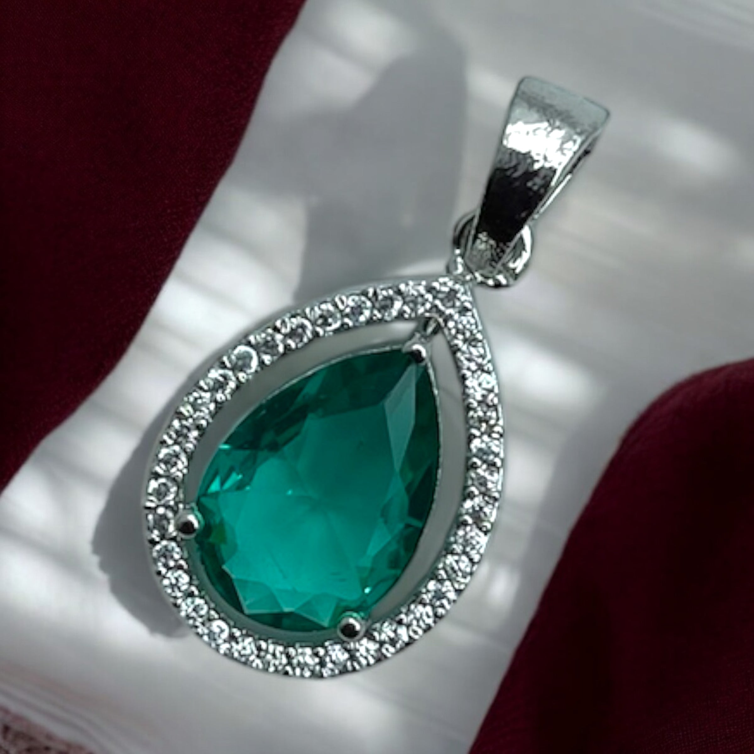 Silver-tone pear emerald pendant with clear stone halo, worn on model with saree