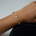 Gold-toned baguette chain bracelet with bezel-set clear stones, worn on wrist