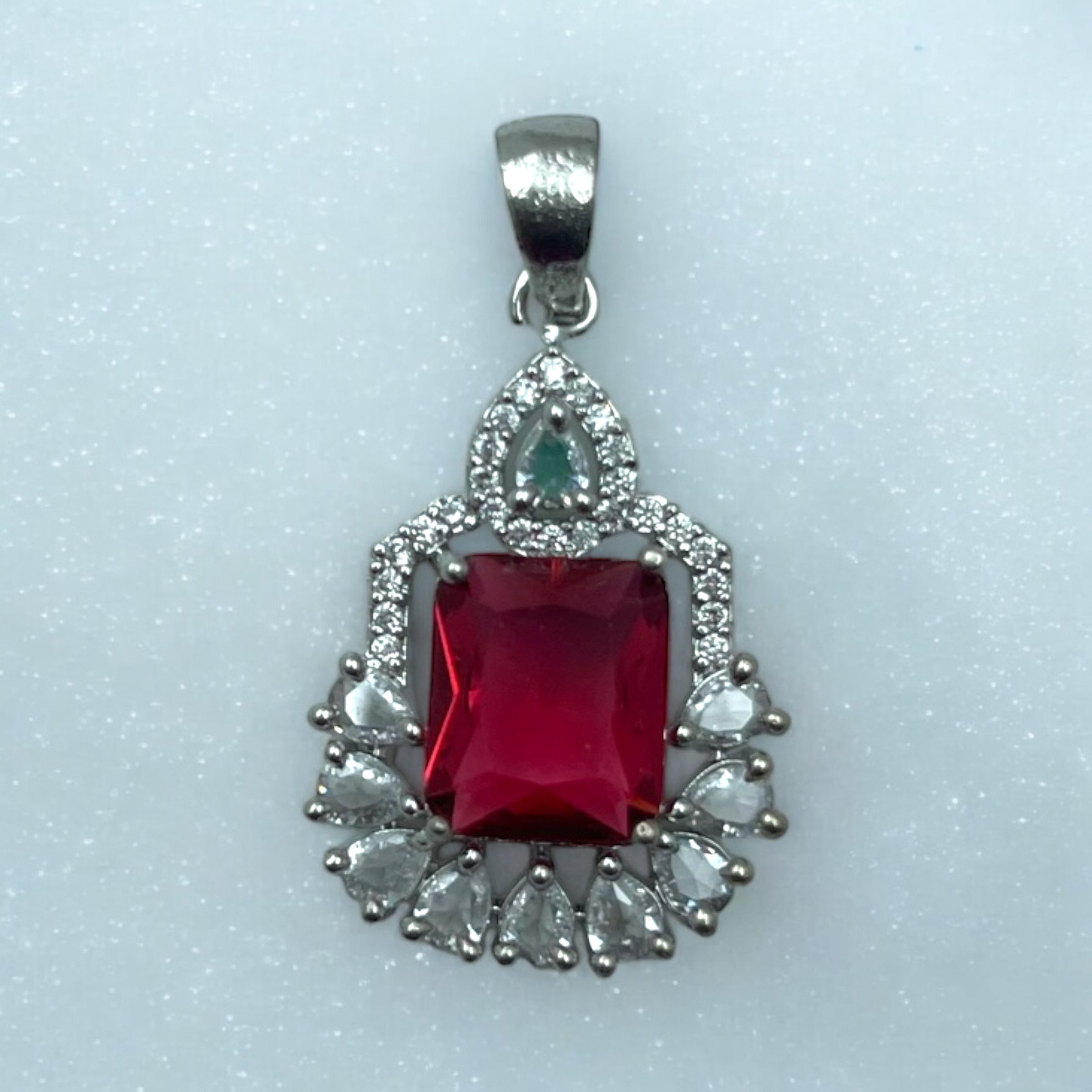 Silver-tone ruby-red pendant necklace with white-stone halo, worn on model with red saree