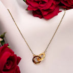 Gold-toned interlocked circle pendant necklace with textured detailing, shown on a display bust with red roses