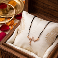 Necklace in a wooden jewelry box with decorative elements and rose petals.