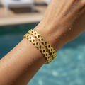 Gold openwork leaf-cluster bangles set worn on wrist by poolside, waterproof