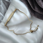Gold-toned bar bracelet with sparkling pave crystals and adjustable slider chain, shown on a wrist with water droplets
