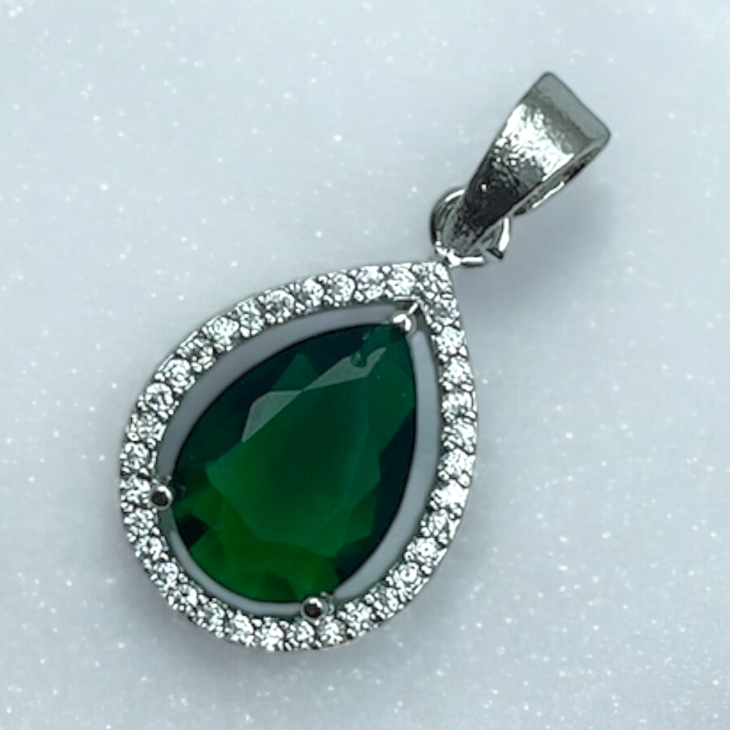 Silver-tone green pear pendant with clear-stone halo, worn on a chain by a woman in a cream saree