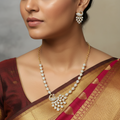 Gold peacock necklace and earrings set with crystal-studded fan tail, worn on model with saree