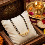 Gold necklace on a white pillow in an ornate wooden box with decorative elements.