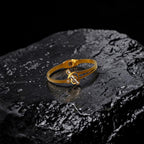 Gold bracelet with a unique design on a dark stone surface