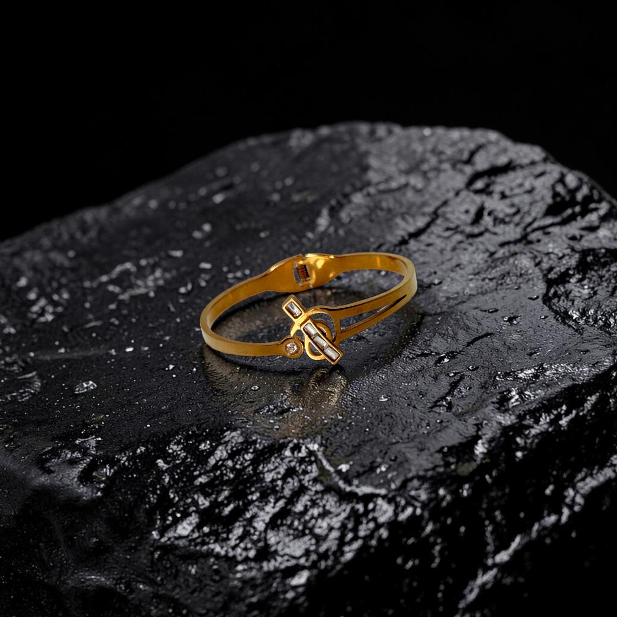 Gold bracelet with a unique design on a dark stone surface