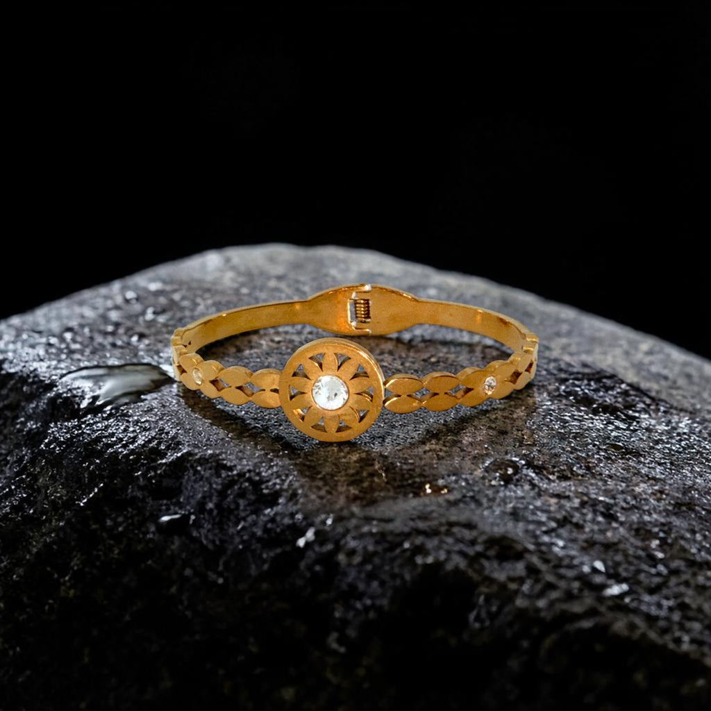 Gold bracelet with a central gemstone on a dark textured surface