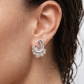 Close-up of an ear wearing a silver earring with floral details.