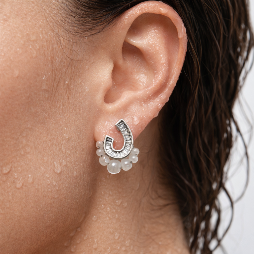 Close-up of an ear wearing a silver earring with floral details.