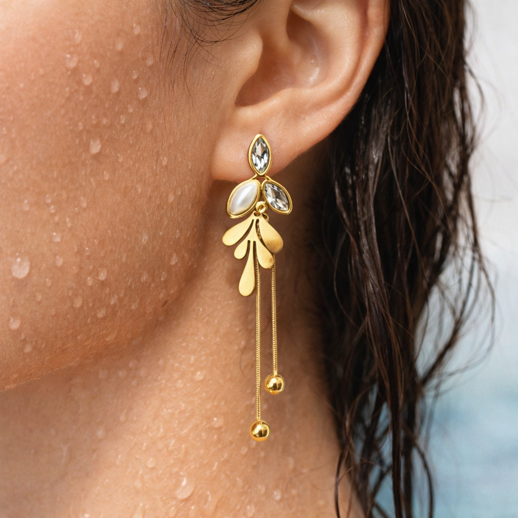 Gold earrings with dangling elements worn by a person
