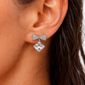 Close-up of an ear wearing a bow-shaped earring with a large central gemstone.
