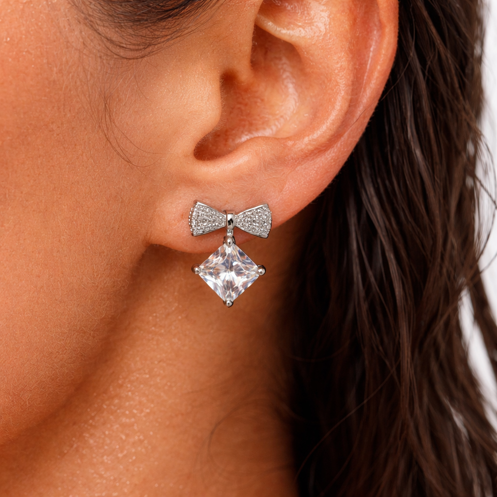 Close-up of an ear wearing a bow-shaped earring with a large central gemstone.