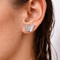 Close-up of an ear wearing a silver butterfly earring with a blurred background