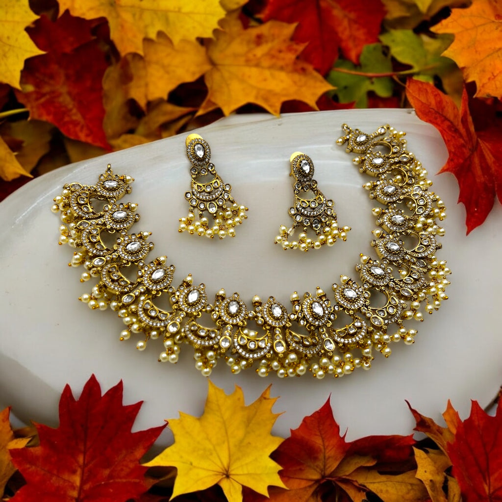 Antique gold Kundan necklace set with white stones and pearl drops, worn by a model in a gold saree