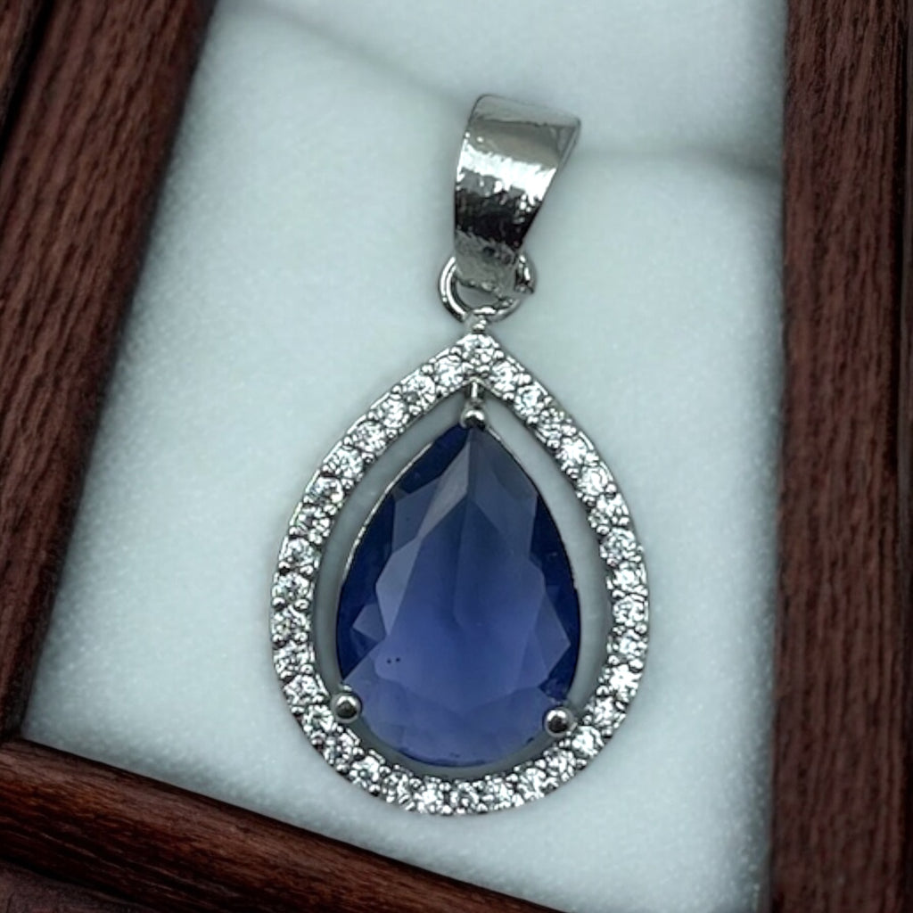 Silver-tone blue drop pendant, pear-shaped blue stone in sparkling crystal halo, close-up flat-lay in box
