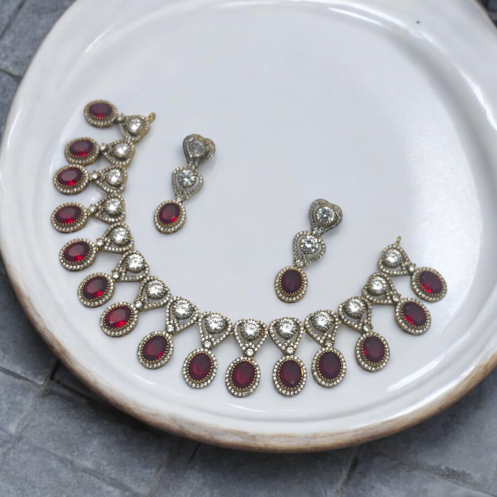Gold-plated red and white stone statement necklace set with drop earrings, flat-lay on white plate