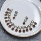 Gold-plated red and white stone statement necklace set with drop earrings, flat-lay on white plate
