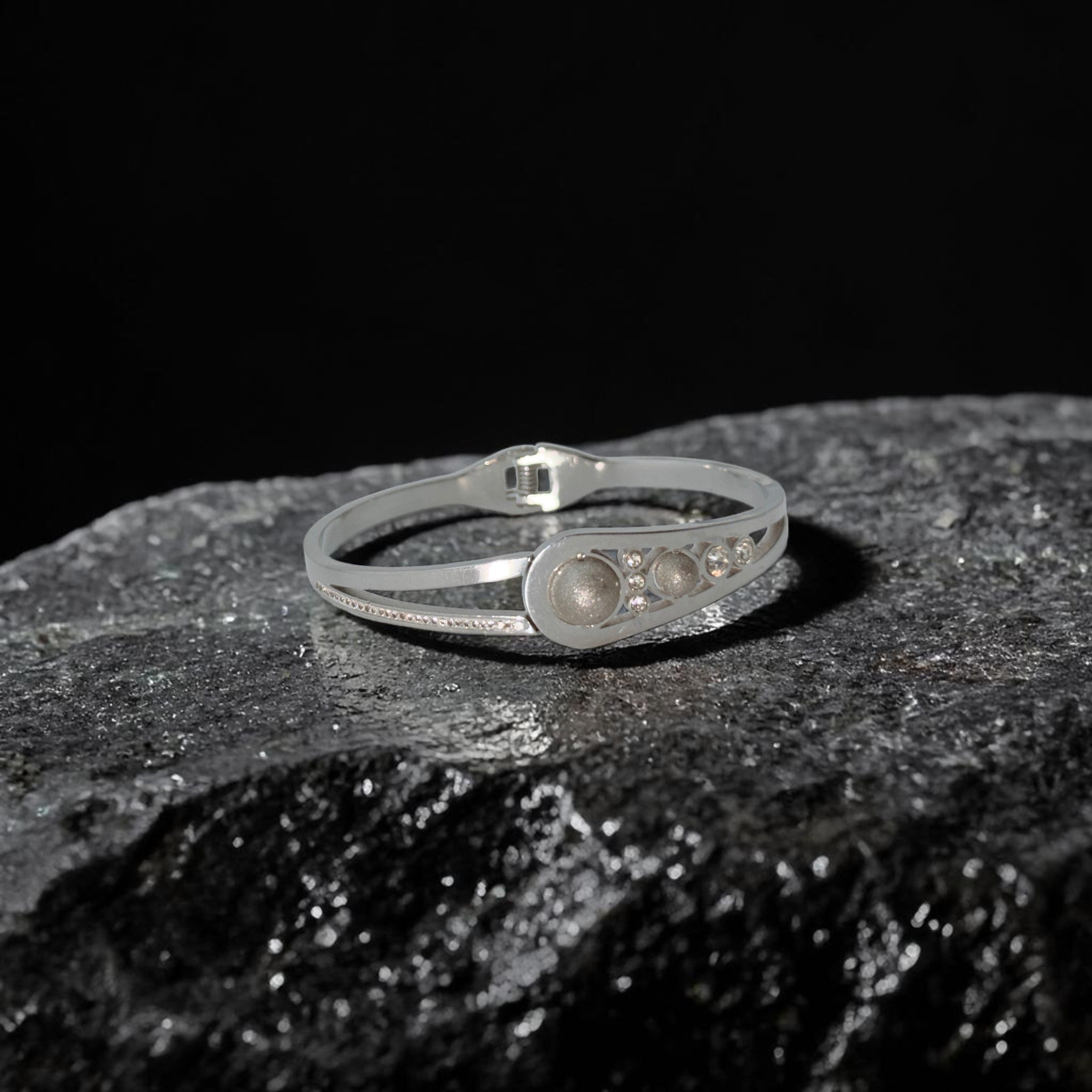 Silver bracelet with embedded stones on a dark stone surface