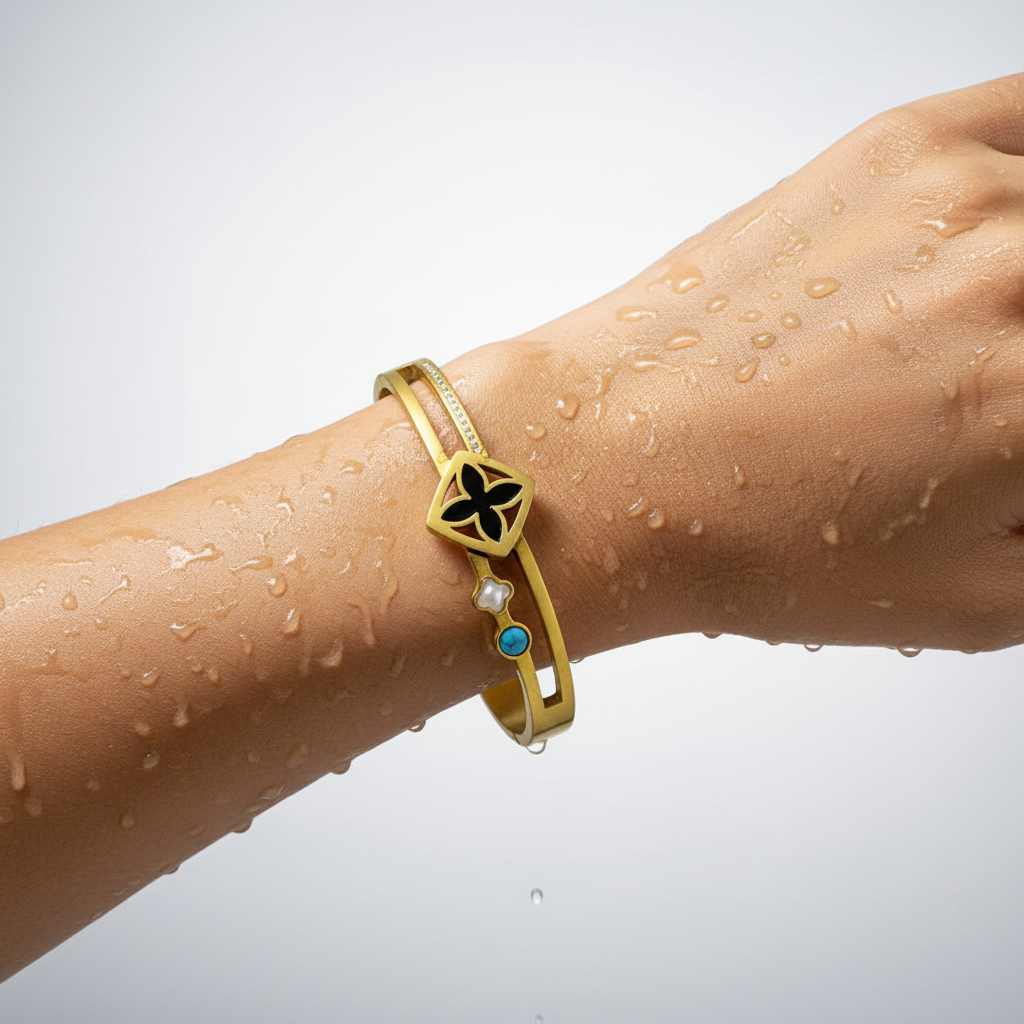 Gold bracelet with a black and blue stone on a wet wrist against a white background