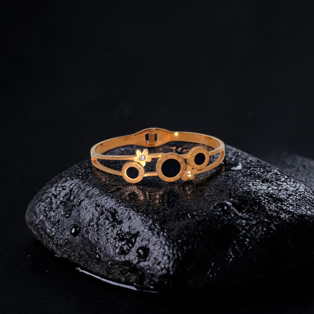 Gold ring with black stones on a dark stone surface