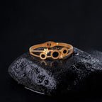 Gold ring with black stones on a dark stone surface