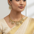 Woman wearing a gold necklace and earrings with a plain background