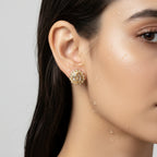 Gold-tone stud earring with teardrop crystal and beaded halo, worn on ear close-up